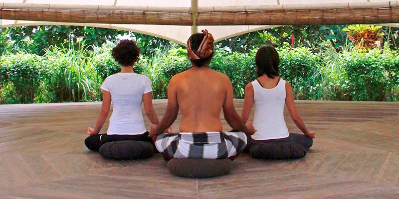 Three guests meditating on the open deck at Bali Silent Retreat