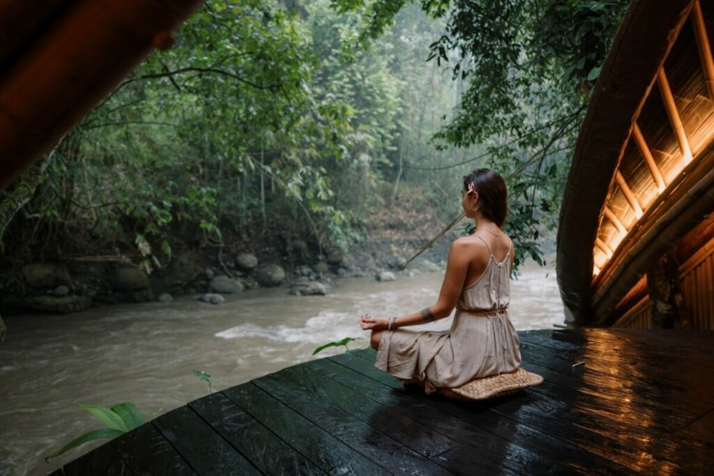 A guest meditating on the bamboo deck above the river at Suenyo