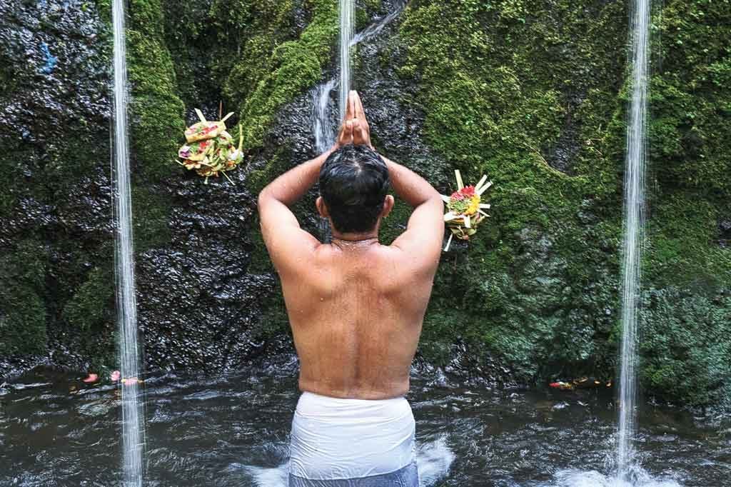 A guest in prayer under a waterfall at Suenyo